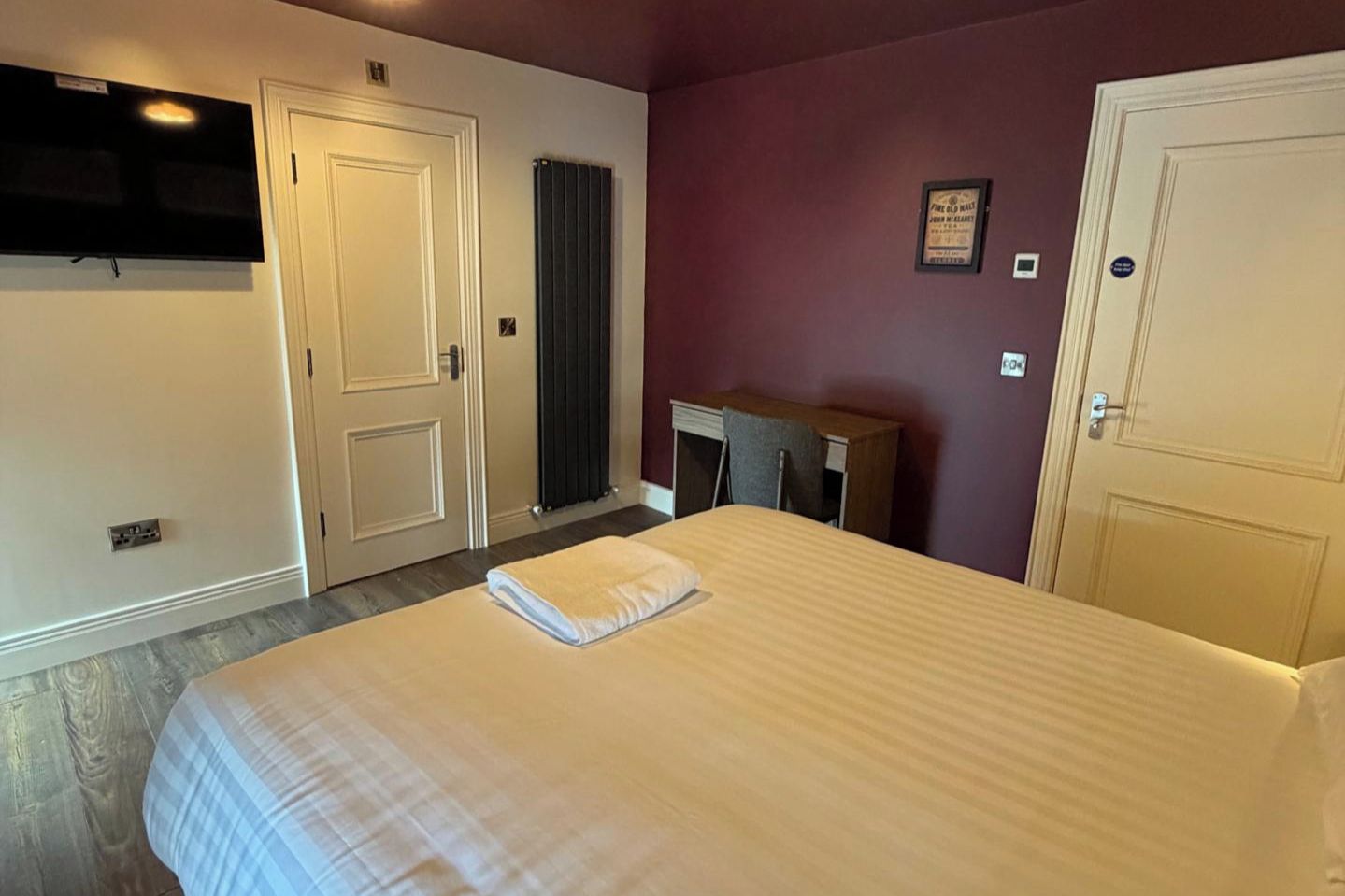 Une chambre d’hôtel équipée d’un lit, d’un bureau, d’une chaise, d’un radiateur et d’une télévision.