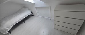 Een slaapkamer met een bed, een ladekast en een deur.