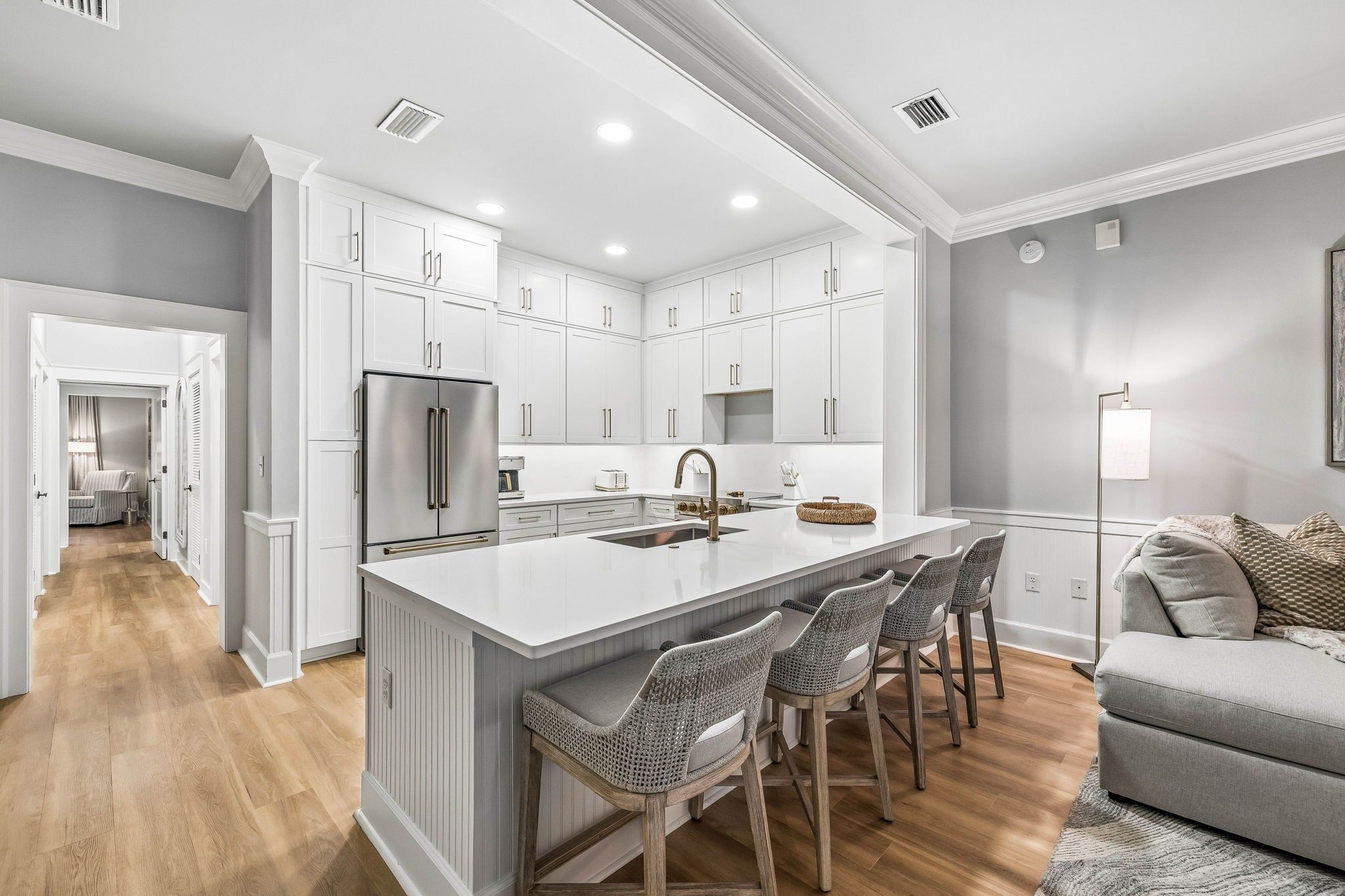 A modern kitchen with a central island, bar stools, and a built-in oven.