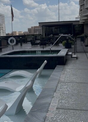 Une piscine au design moderne, une bouée de sauvetage et un panneau indiquant qu’il est interdit de plonger.