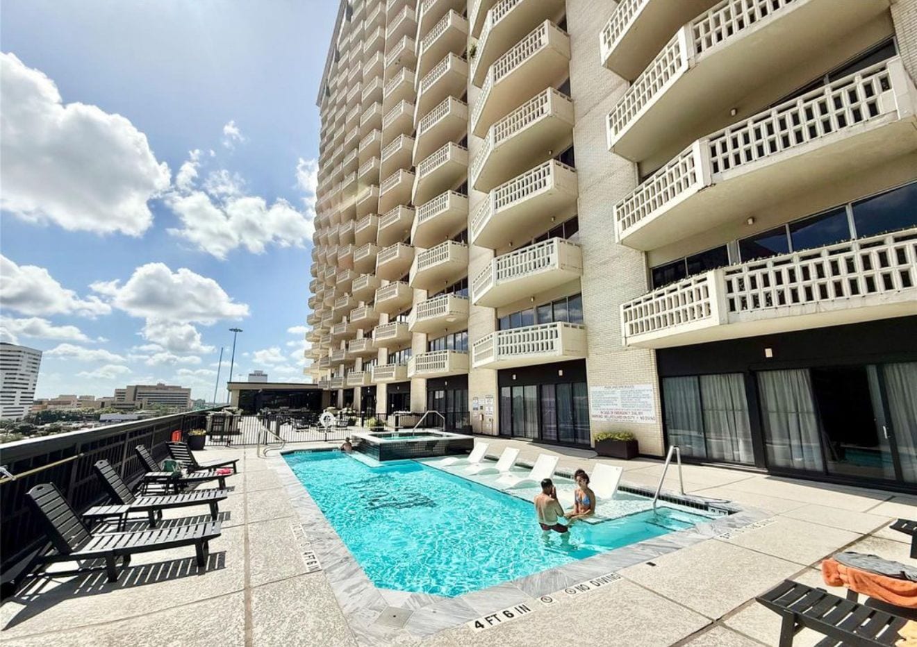 A rooftop pool area with lounge chairs and a swimming pool.