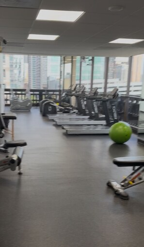Une salle de sport équipée de matériel d’exercice et dotée de grandes fenêtres.