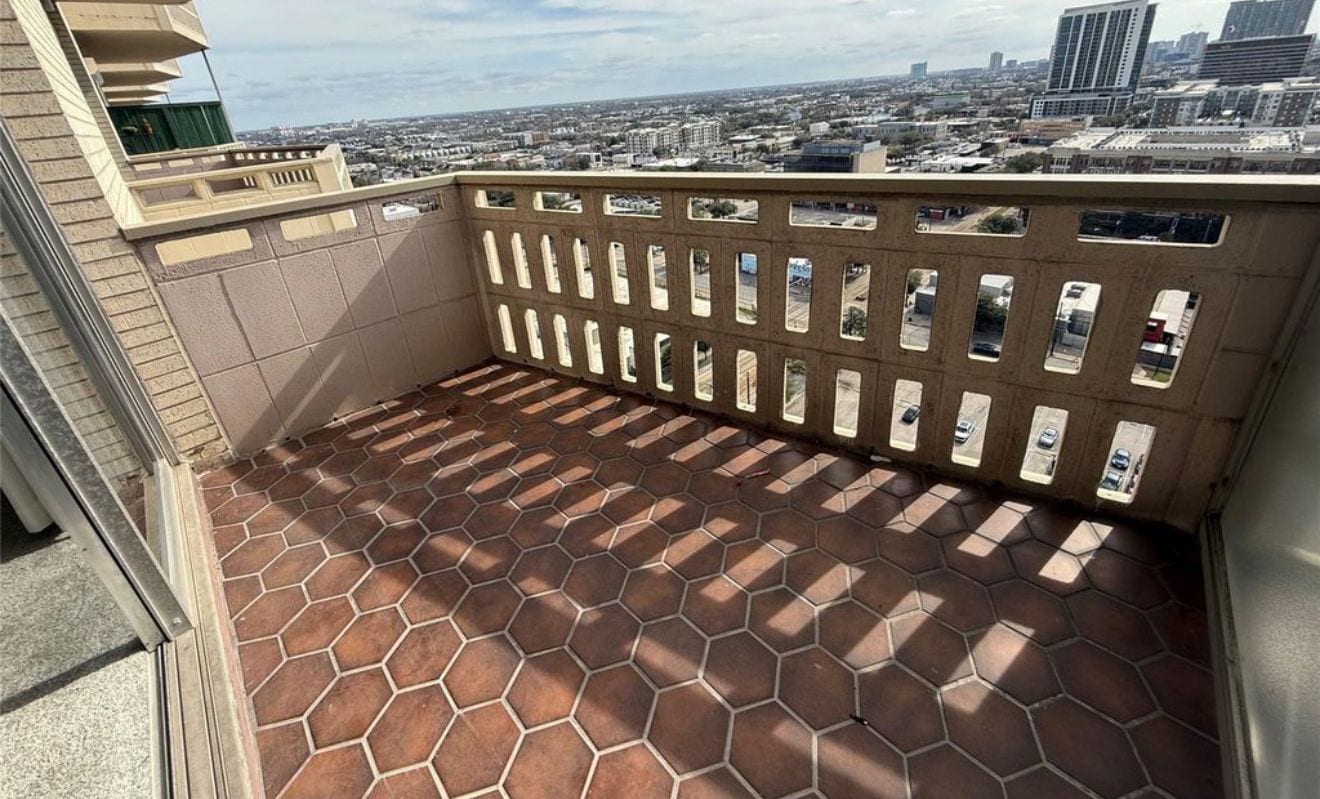 Un balcón con suelo de baldosas y barandilla de metal.