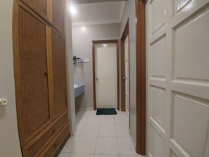 A hallway with a wooden wardrobe, a white door, and a bathroom with a sink.