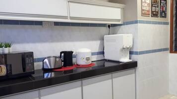 Une cuisine équipée d’un four à micro-ondes, d’un grille-pain et d’une machine à café, le tout posé sur le plan de travail.