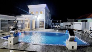 A swimming pool with a water feature, a building with a white facade, and outdoor seating. - Melaka A’Famosa Grand Pool Villa – Private Pool & Family Getaway (Alor Gajah)