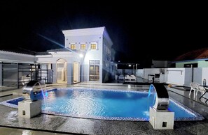 A swimming pool with a water feature, a building with a white facade, and outdoor seating. - Melaka A’Famosa Grand Pool Villa – Private Pool & Family Getaway (Alor Gajah)