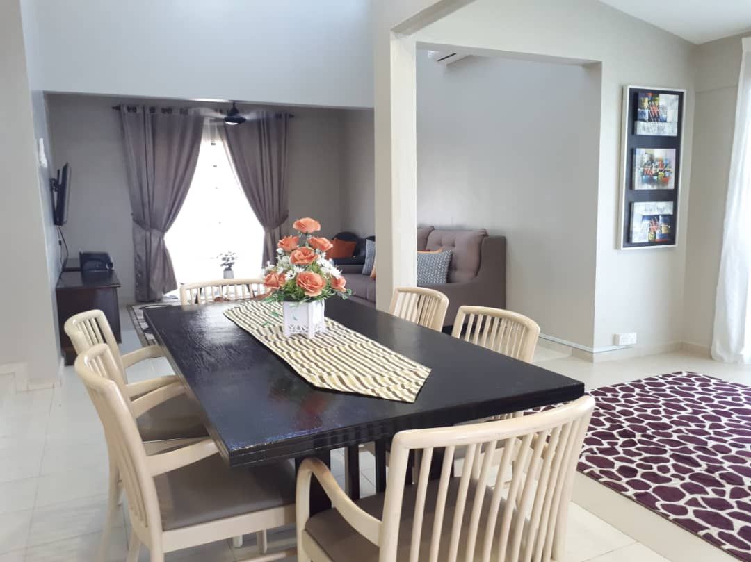 Un coin repas avec une table noire, des chaises de couleur beige, un vase avec des fleurs et un set de table à motifs.
