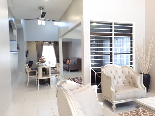 A modern living room with a sofa, dining chairs, and a ceiling fan.