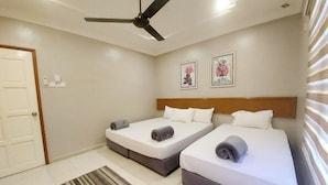 A hotel room with two beds, a ceiling fan, a door, and a striped rug.