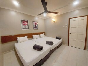 A hotel room with a large bed, a ceiling fan, two wall-mounted light fixtures, and a door.