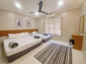 A hotel room with two beds, a ceiling fan, an air conditioning unit, a window with blinds, and a small desk with a mirror. - Melaka A’Famosa Grand Pool Villa – Private Pool & Family Getaway (Alor Gajah)