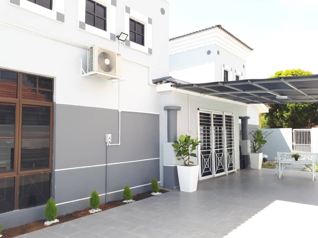 A modern building with a covered patio area, a large window, and a small garden.