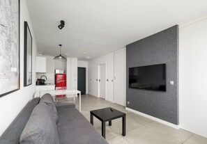 A modern living room with a sofa, a coffee table, and a flat-screen TV mounted on a textured wall. - City Center Śliska Apartment (Warszawa)