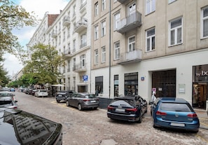 A street with parked cars, a building with multiple floors, and a storefront with a sign. - Poznańska City Center Soul Apartment (Warszawa)