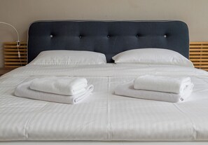 A neatly made bed with white linens and two folded towels. - Poznańska City Center Soul Apartment (Warszawa)