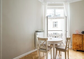 Een kamer met een witte tafel en stoelen, een radiator en een houten kast.