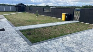 A paved outdoor area with a pathway, a small tree, and a trash bin. - Stodoła Kuczki Wieś Cottage (Kuczki-Wieś)