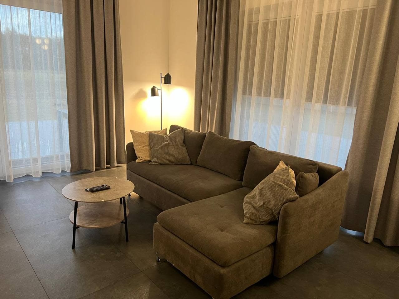Una sala de estar con un sofá modular, una mesita redonda y una lámpara de pie.