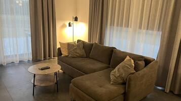 Una sala de estar con un sofá modular, una mesita redonda y una lámpara de pie.