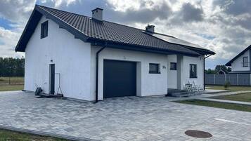 A modern two-story house with a garage, a paved driveway, and a small garden area.
