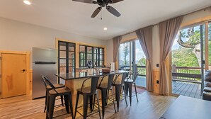 Una cocina moderna con una isla central, taburetes de bar y vistas al exterior.
