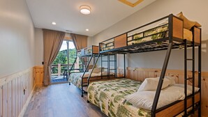 Habitación con literas, suelo de madera, ventana con cortinas y vistas al exterior.