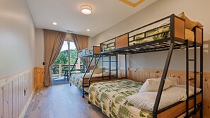 A bunk bed room with a wooden floor, a window with curtains, and a view of greenery outside. - The Courtside Suites at Beatitude Barn (Maggie Valley)
