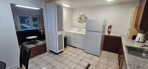 Een compacte keuken met een wasmachine, een koelkast, een spoelbak en een raam met uitzicht op een straat.