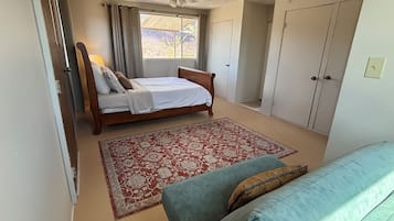 Een slaapkamer met een bed, een plafondventilator, een raam met gordijnen, een kledingkast en een bank.