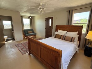 A bedroom with a wooden bed, a chair, a ceiling fan, and a window. - Remote Alamo Lake Getaway!  Dark night skies. AZPT. Fishing. Farm. Ghost town. (Yucca)