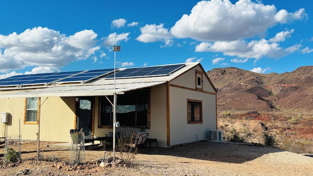 Un edificio de una planta con techo inclinado, paneles solares y cielo despejado.