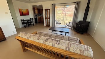 Een woonkamer met een bank, een eettafel, een keuken op de achtergrond en een open haard.