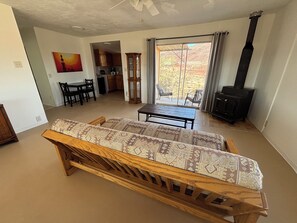 Una sala de estar con sofá, mesa de comedor, cocina al fondo y chimenea.