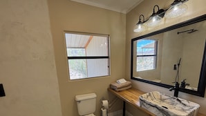Un baño con inodoro, lavabo, espejo y ventana.