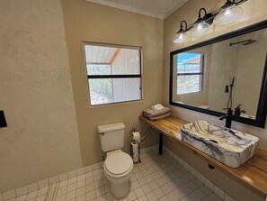 A bathroom with a toilet, sink, mirror, and window. - Remote Alamo Lake Getaway!  Dark night skies. AZPT. Fishing. Farm. Ghost town. (Yucca)