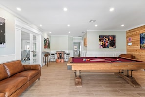 A pool room with a pool table, a sofa, and a bar area. - Waterfront 4BR + deep water+ 2 Docks + Outdoor Kitchen, Sleeps 11 (Ruskin)