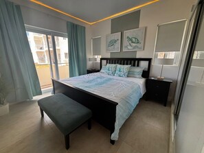 A bedroom with a bed, bench, nightstands, and artwork on the walls. - New stylish,1 BR, Resort access, SOV - Sea-Esta (Sosua)