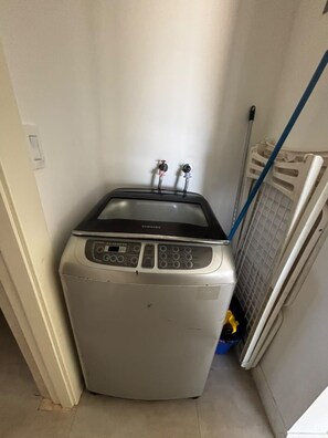 A compact washing machine in a narrow space with a visible water inlet and outlet. - New stylish,1 BR, Resort access, SOV - Sea-Esta (Sosua)