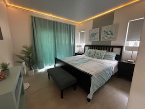 Ein modernes Schlafzimmer mit Bett, Nachttischen, einer Bank, einem Schreibtisch und einem Fenster mit Vorhängen.