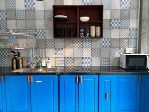 Una cucina con piastrelle decorative, un forno a microonde e mobili azzurri.