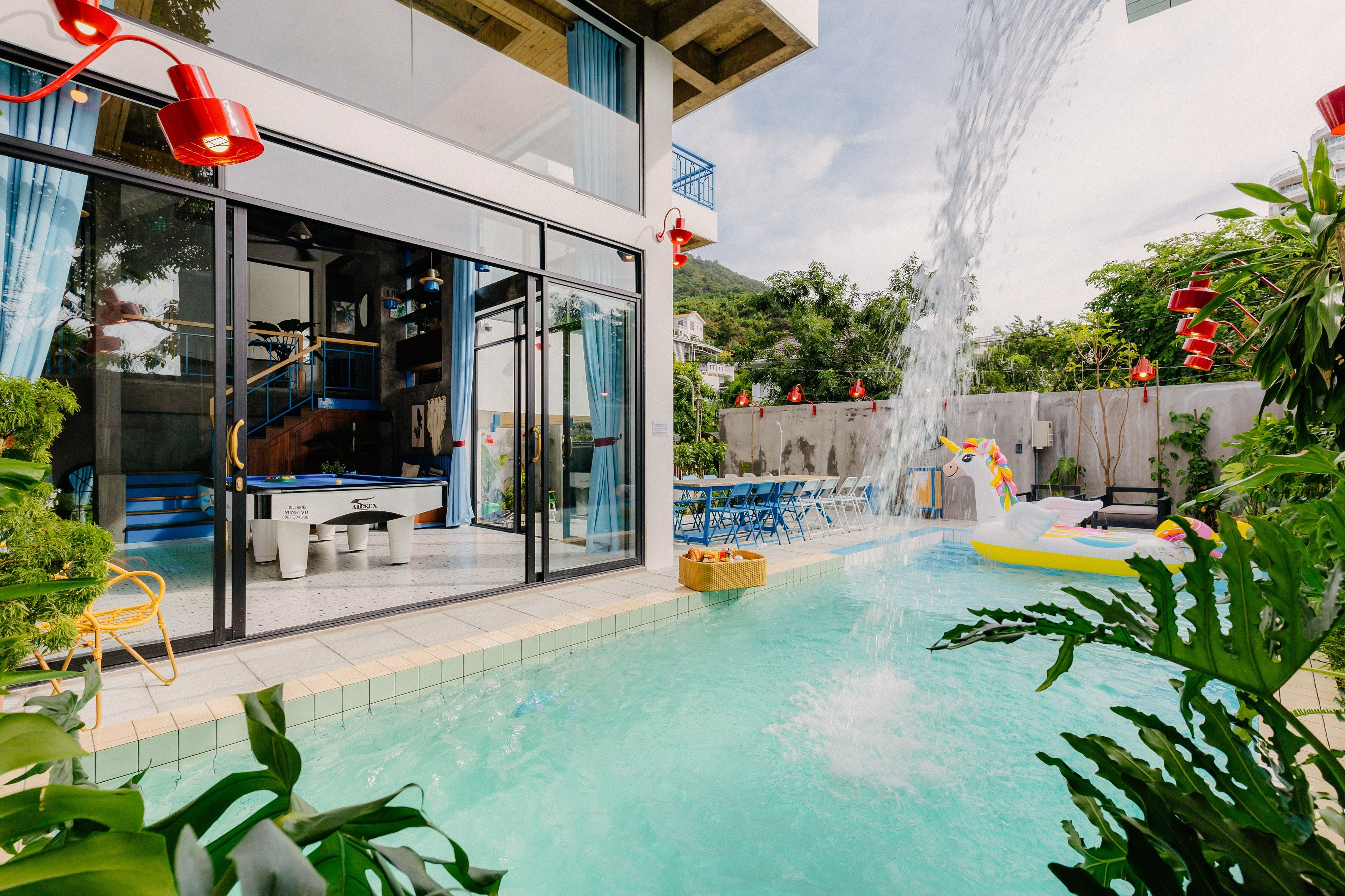 Uma área de piscina moderna com uma sala envidraçada, um elemento aquático e mobiliário para áreas externas.
