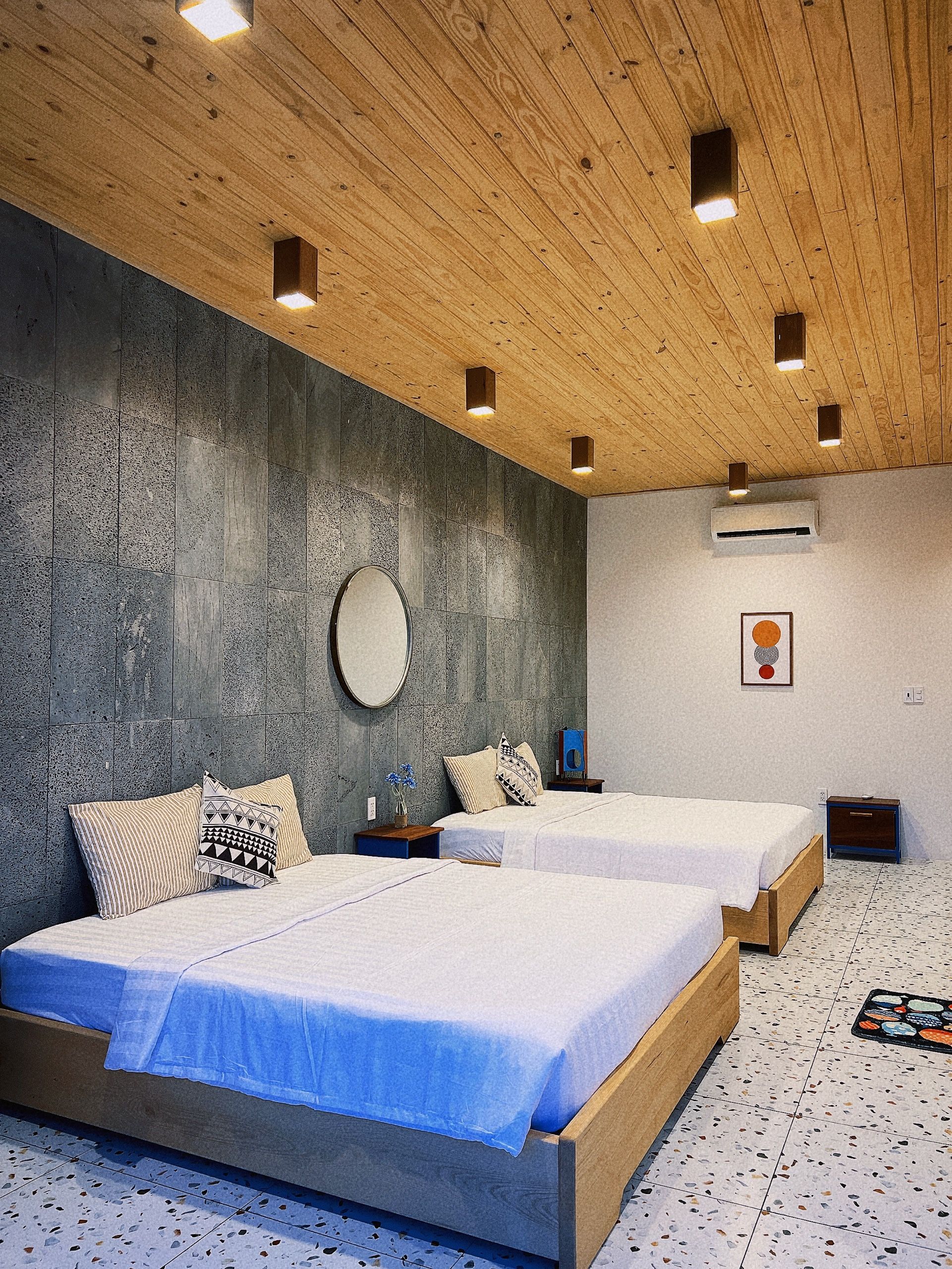 Una camera da letto moderna con due letti, un grande specchio e un soffitto in legno con illuminazione a incasso.