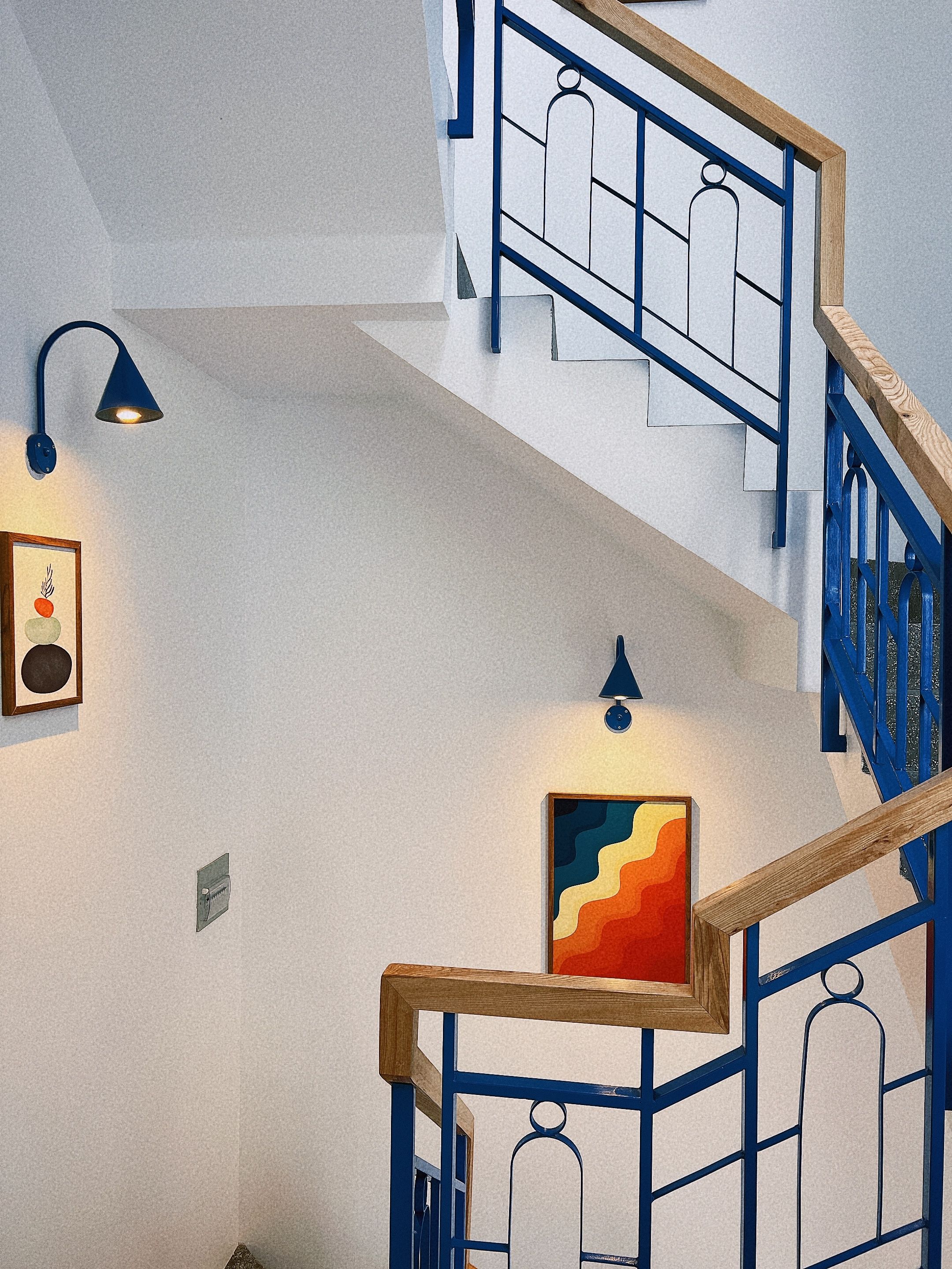 Una scala con ringhiere blu e corrimano in legno, che conduce a un livello superiore.