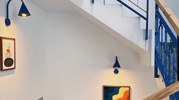 Una scala con ringhiere blu e corrimano in legno, che conduce a un livello superiore.