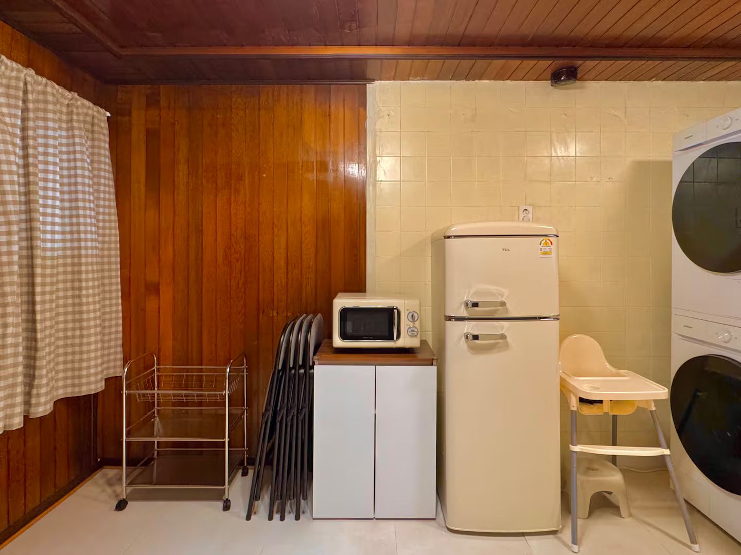 A compact kitchen with a microwave, a refrigerator, and a washing machine.