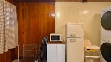 A compact kitchen with a microwave, a refrigerator, and a washing machine.