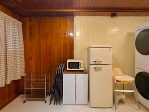 A compact kitchen with a microwave, a refrigerator, and a washing machine.