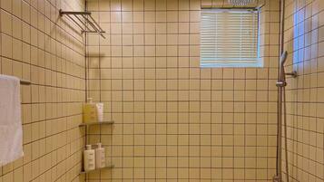 A bathroom with a shower, a sink, and a window.