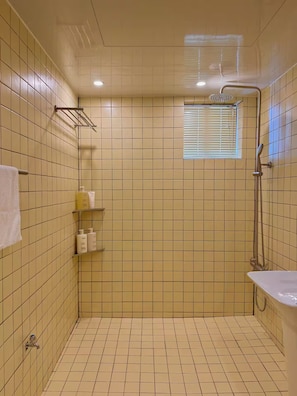 A bathroom with a shower, a sink, and a window.